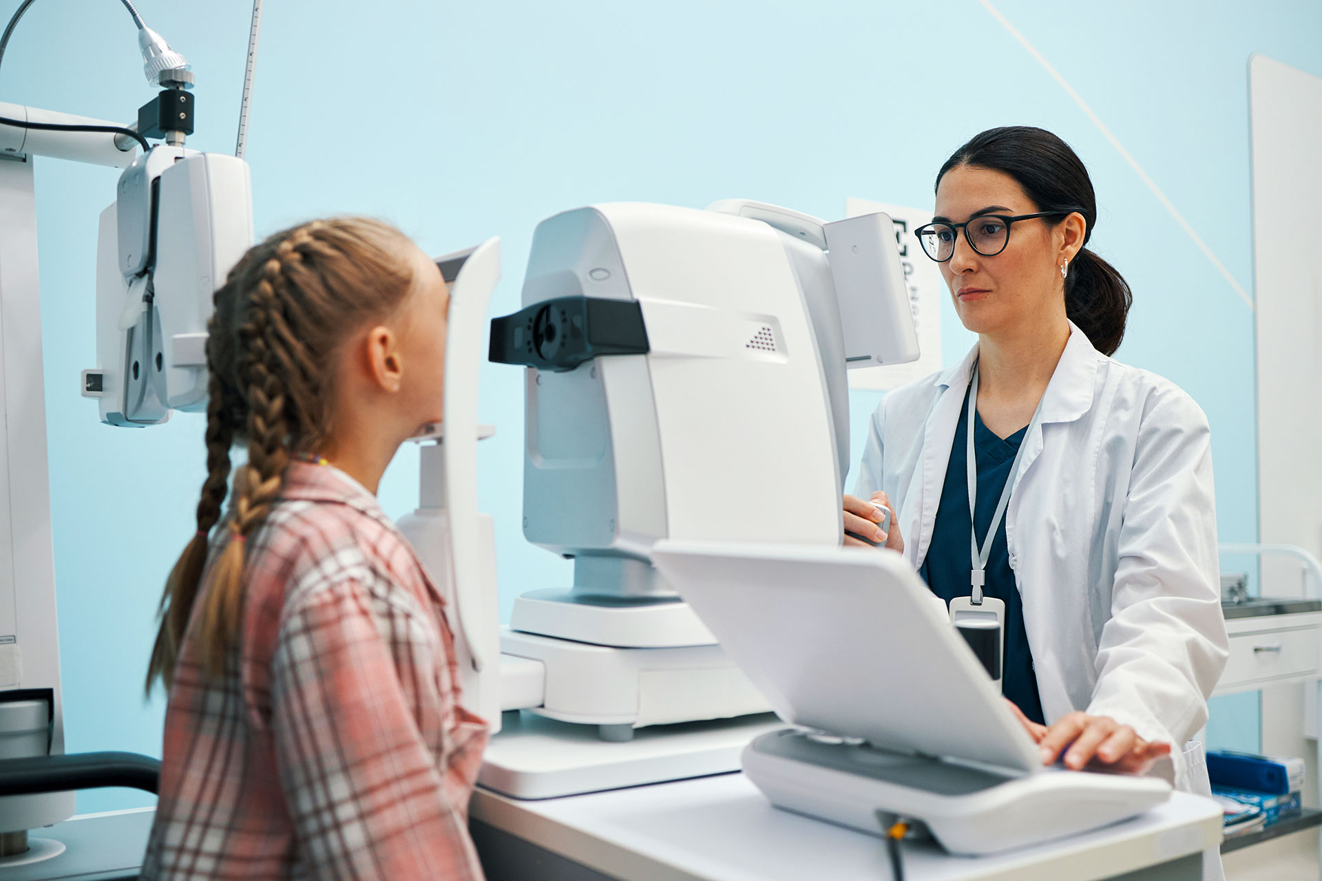 Optometrist adjusting equipment during child eye exam